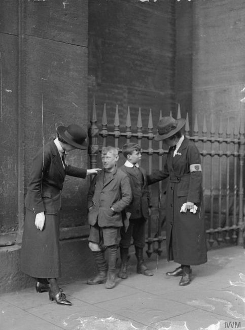 A female police patrol warning small boys outside of Euston Station, 1918. © IWM (Q 31089)