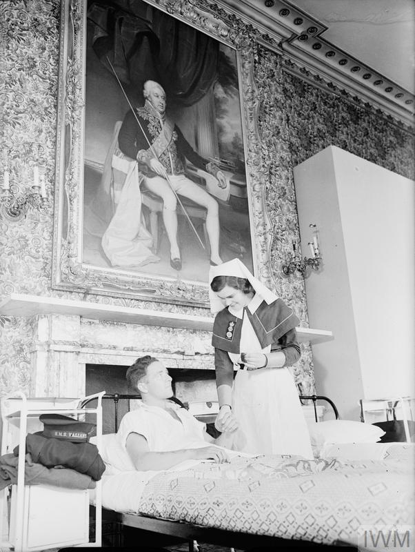QAIMNS Sister taking the pulse of a patient at Cholmondeley Castle. © IWM (A 11529)