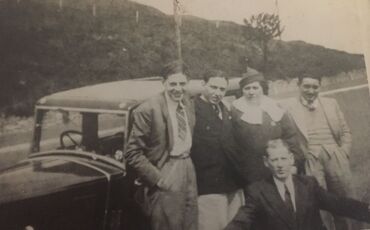 In front of Solomon's car. Solomon is at the bottom, Esther is above him. On her left are Manny and Max and there is an unknown gentleman on the right.