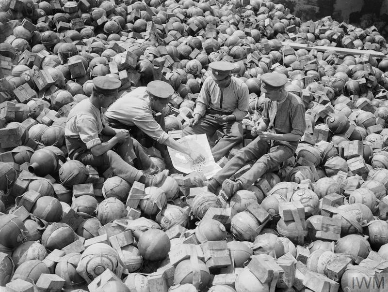Soldiers playing cards in a trench of mortar ammunition (known to British troops as 'toffee apples') at Acheux, July 1916. © IWM (Q 1375)