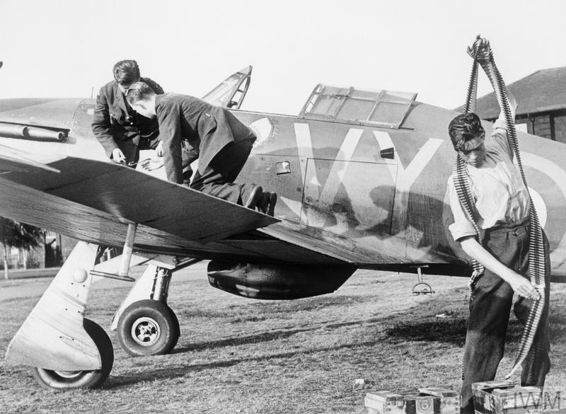 Two armourers service the machine guns of a Hawker Hurricane Mk I of No. 85 Squadron, while a third unpacks belts of .303 inch ammunition at RAF Debden, 25 July 1940.